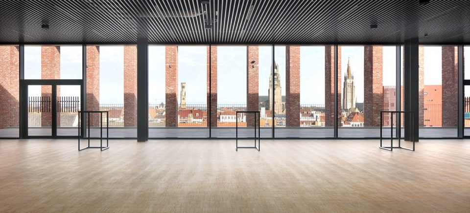 A top-floor room at the BMCC, floor-to-ceiling windows looking out over the towers of Bruges.